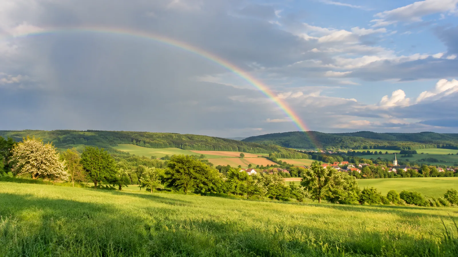 Duha nad venkovskou krajinou